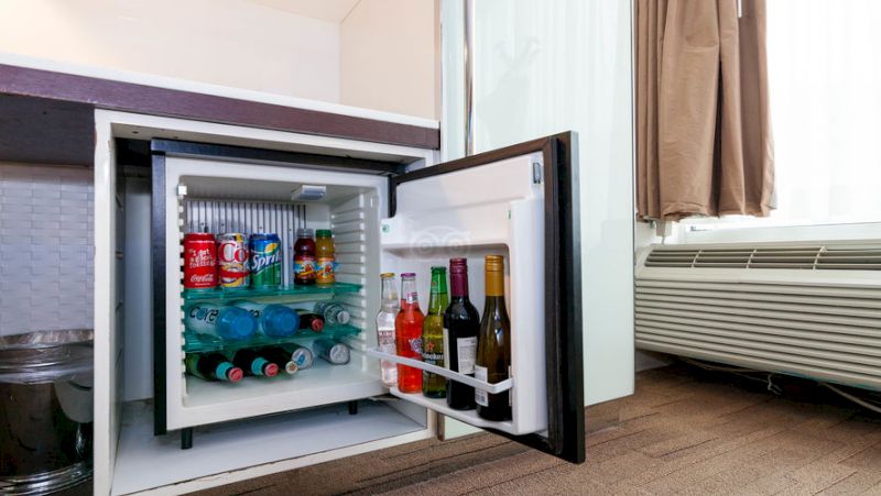 An open mini-fridge stocked with drinks and bottles.