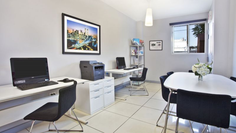A well-lit office space with workstations, a meeting table, and modern furniture.
