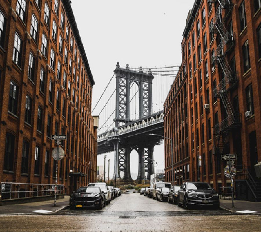 A street with brick buildings and a bridge in the background