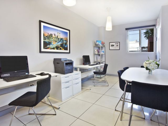 A business center with two desks, a printer, and a meeting table