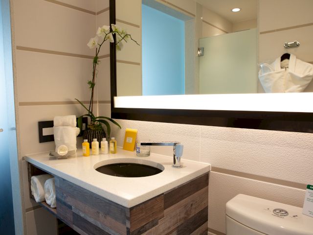 A clean bathroom sink area with a white countertop, wood accents, and a large mirror above the sink.