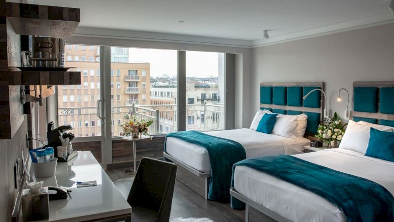 A hotel room with two beds, a desk, and a large window