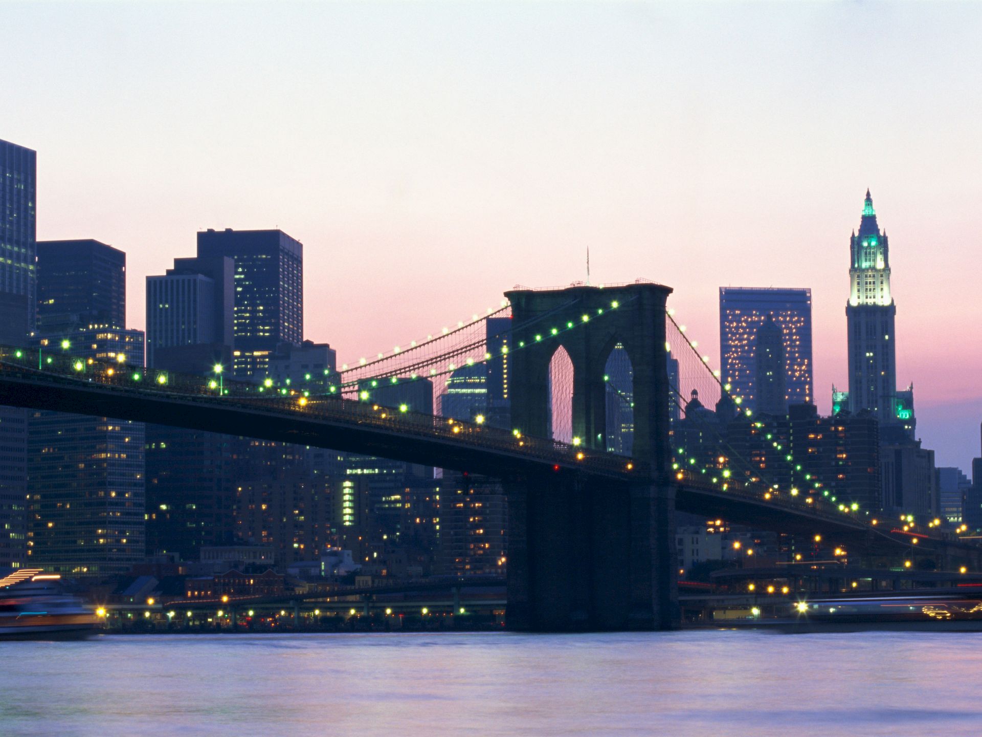 A city skyline at dusk with a bridge over water