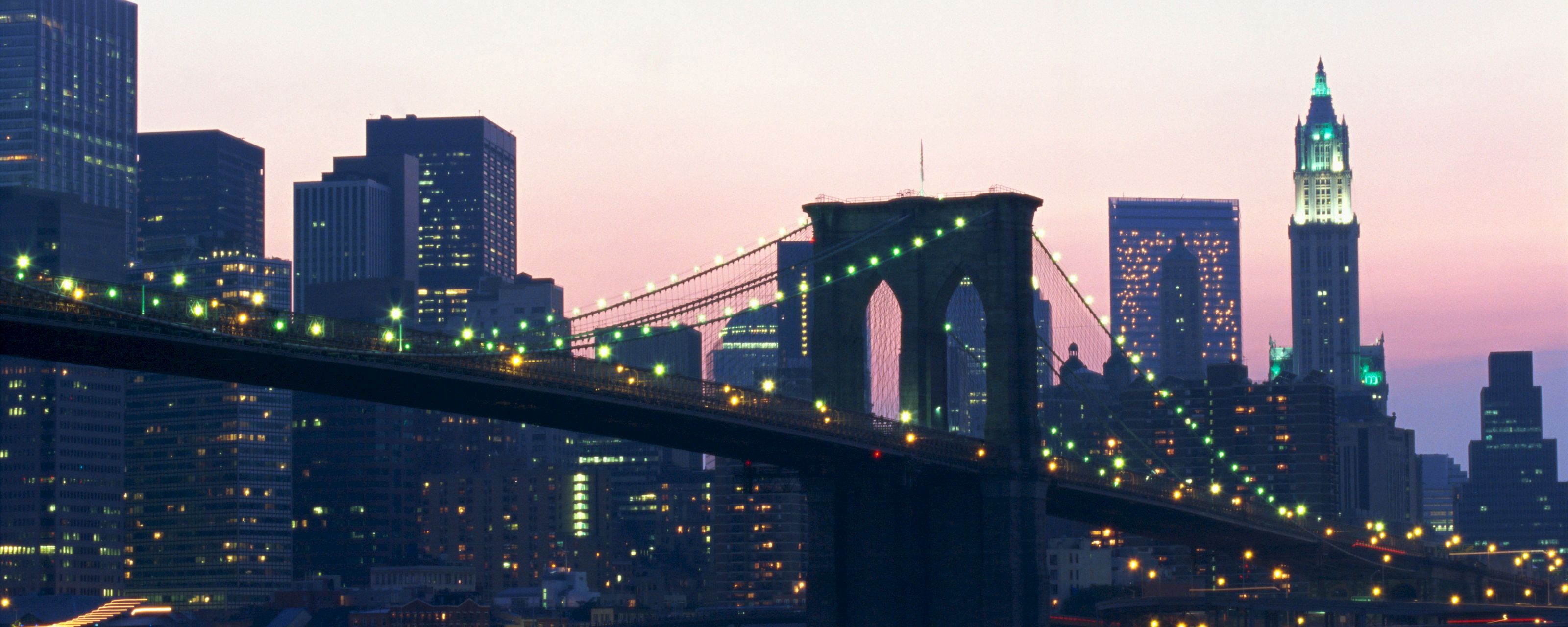 a cityscape at dusk with a bridge and skyscrapers