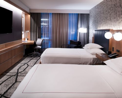 A hotel room with two twin beds, a desk, and a TV