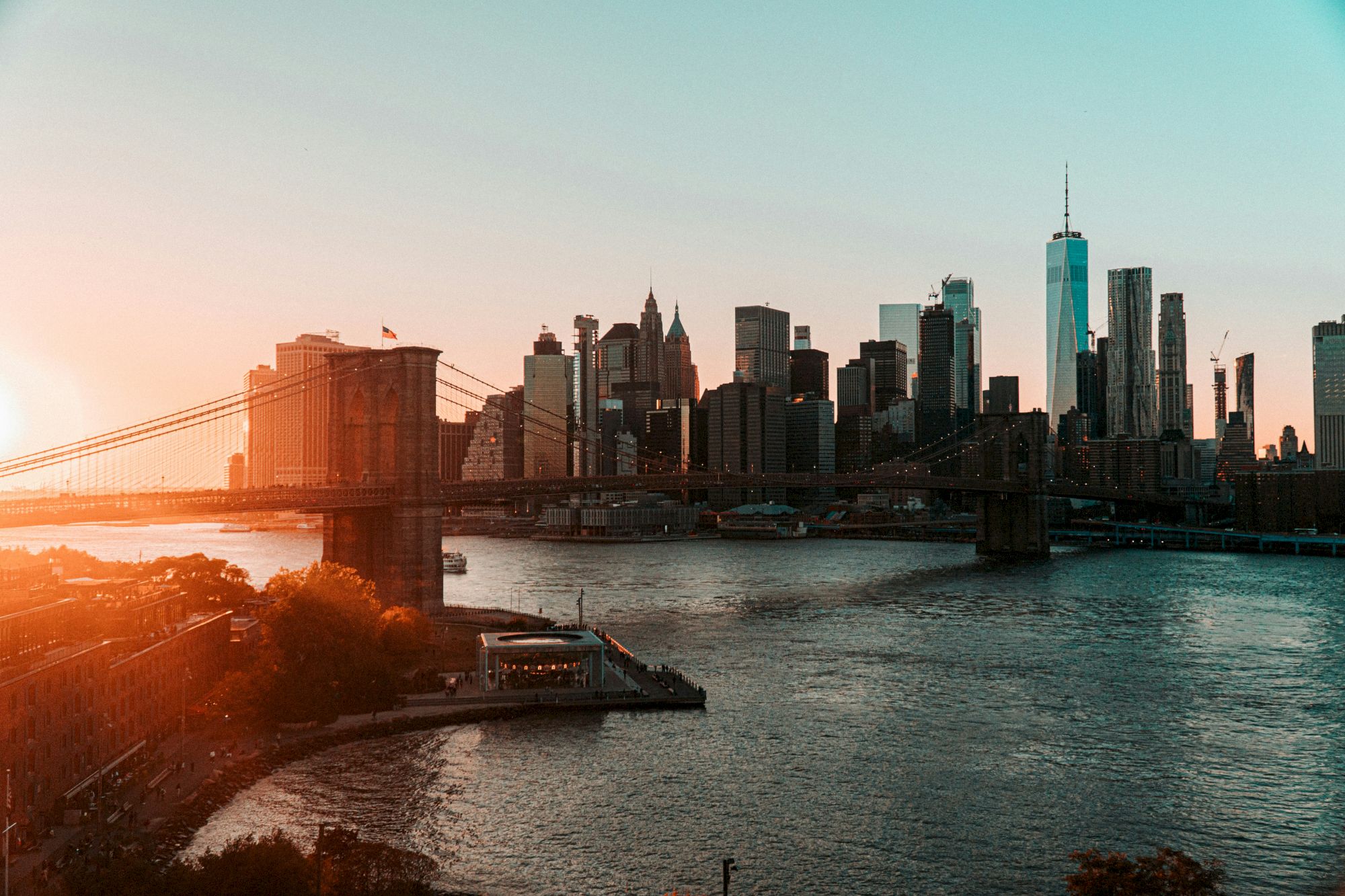 The image shows a sunset view of a city skyline with a prominent bridge over a river, likely capturing an iconic urban landscape.